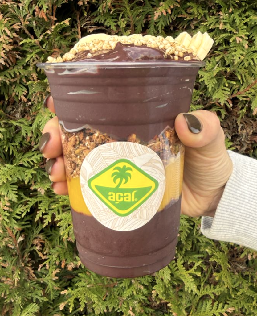 Acai cup vastgehouden in een hand, met Acai softserve uit een Acai machine of Acai softijsmachine
